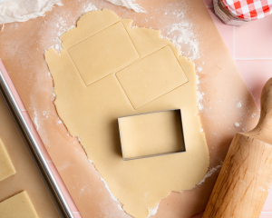 Cutting rectangles out of pie crust rolled into a thin sheet.