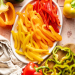 Bell peppers sliced into strips and rings and placed on a white oval plate.