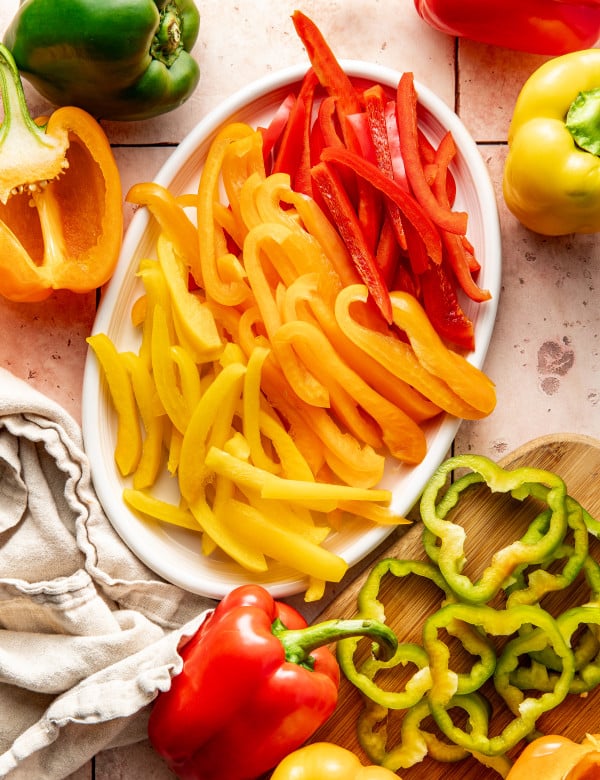 Bell peppers sliced into strips and rings and placed on a white oval plate.