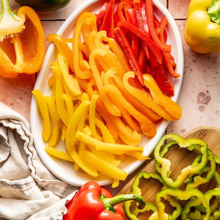 Bell peppers sliced into strips and rings and placed on a white oval plate.