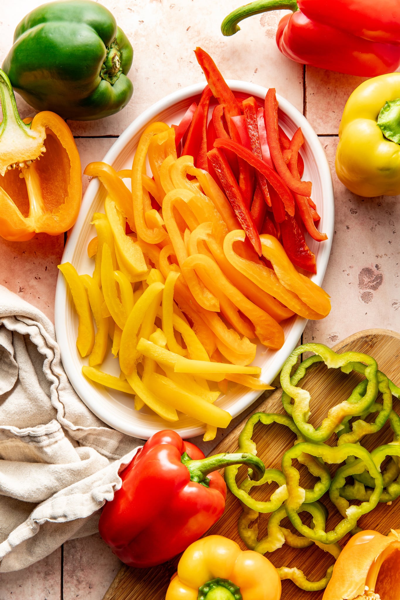 Bell peppers sliced into strips and rings and placed on a white oval plate.