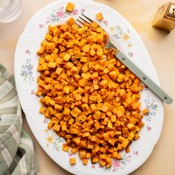 Cooked sweet potatoes on a large oval serving plate with fork on the right side.