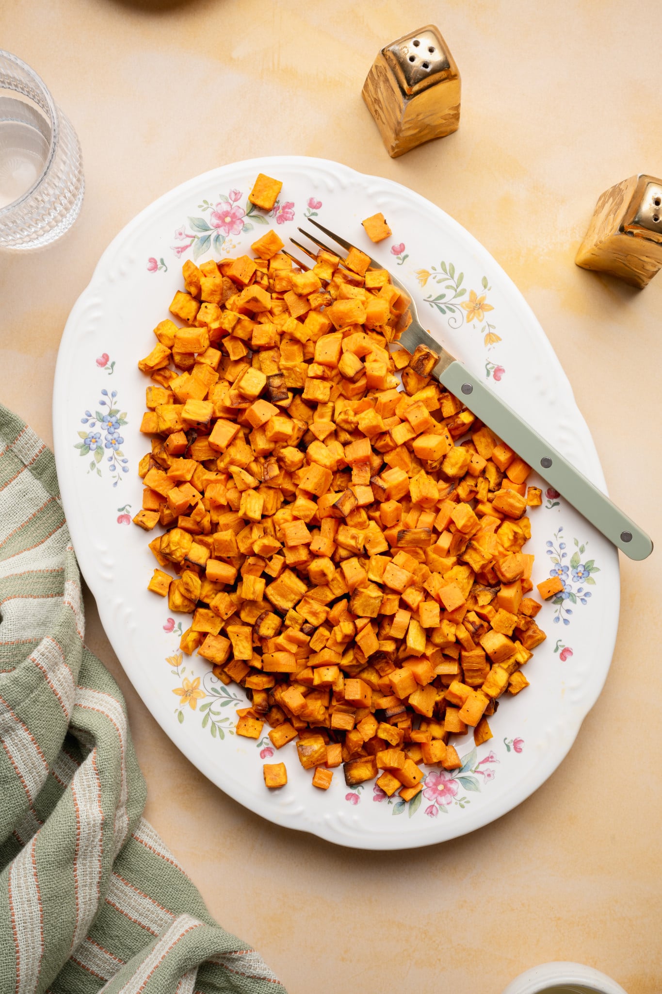 Cooked sweet potatoes on a large oval serving plate with fork on the right side.
