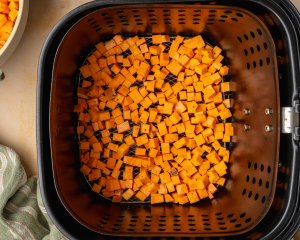 Cubes sweet potatoes in the bottom on an air fryer.