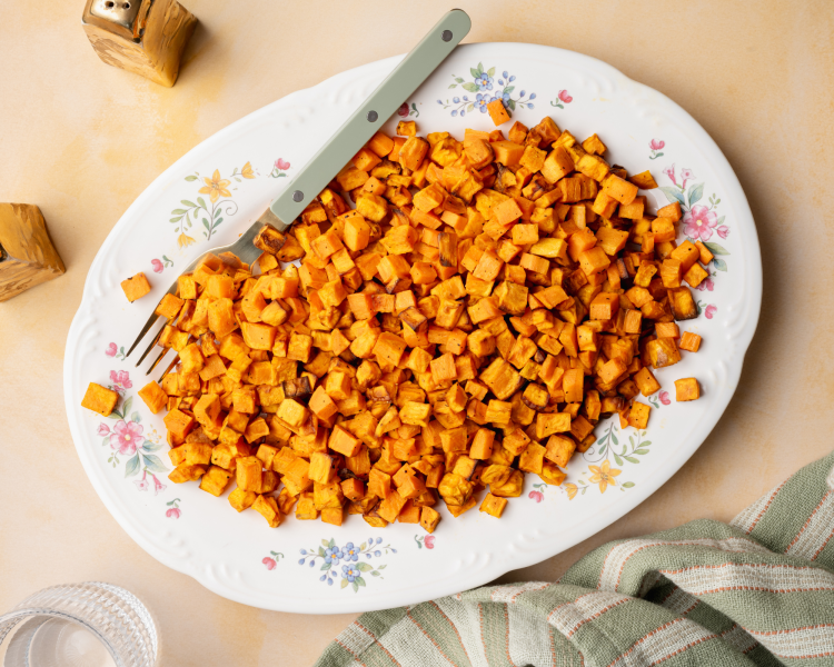 Cooked sweet potatoes served on a floral plate with fork on the side.