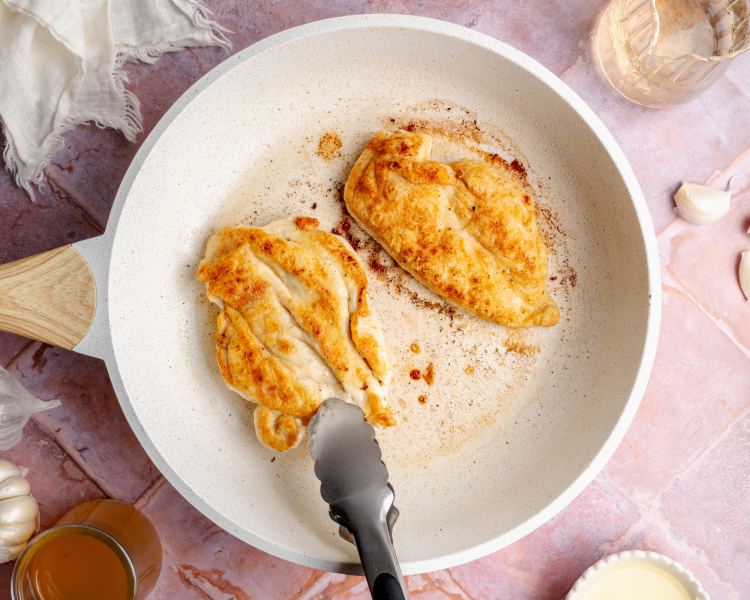 Searing two chicken breasts in a pan.