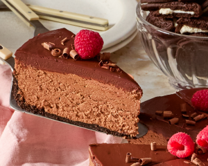 Removing a slice of chocolate cheesecake with a cake server.