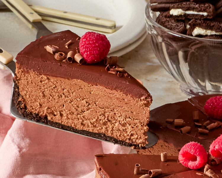 Removing a slice of chocolate cheesecake with a cake server.