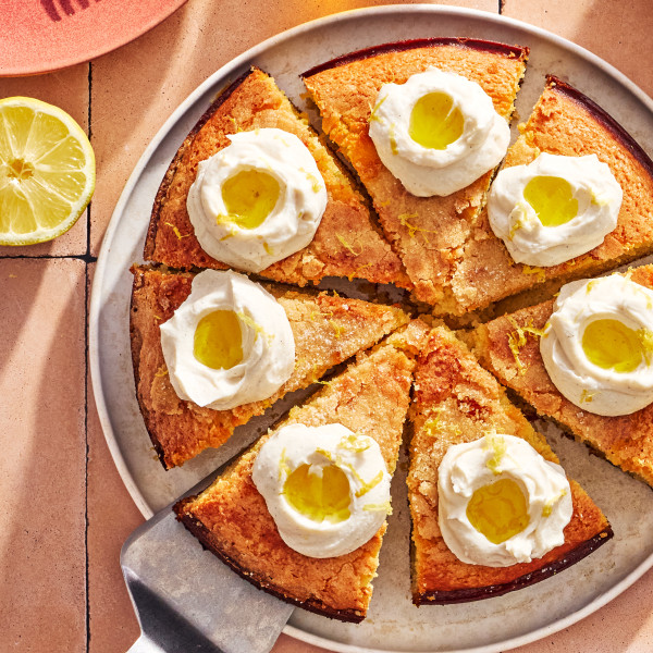 Lemon olive oil ricotta cake sliced and topped with dollops of whipped ricotta topping, olive oil and lemon zest.