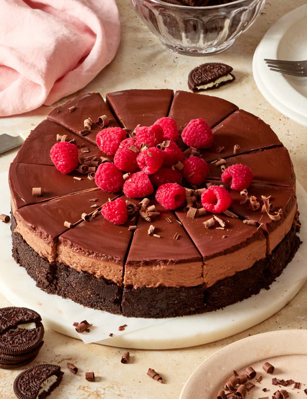 No-bake chocolate cheesecake sliced and topped with fresh raspberries and chocolate shavings.
