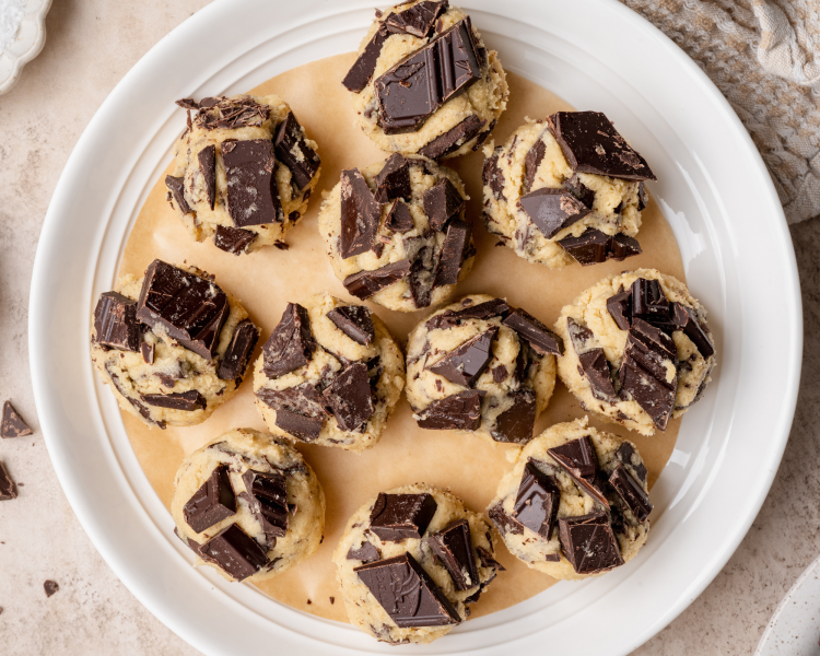 11 chocolate chunk cookies rolled into balls and placed on a parchment lined plate to chill in the freezer for 15-30 minutes before baking.