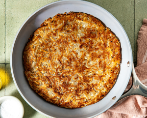 Potato pancake flipped in skillet to cook on the bottom side.