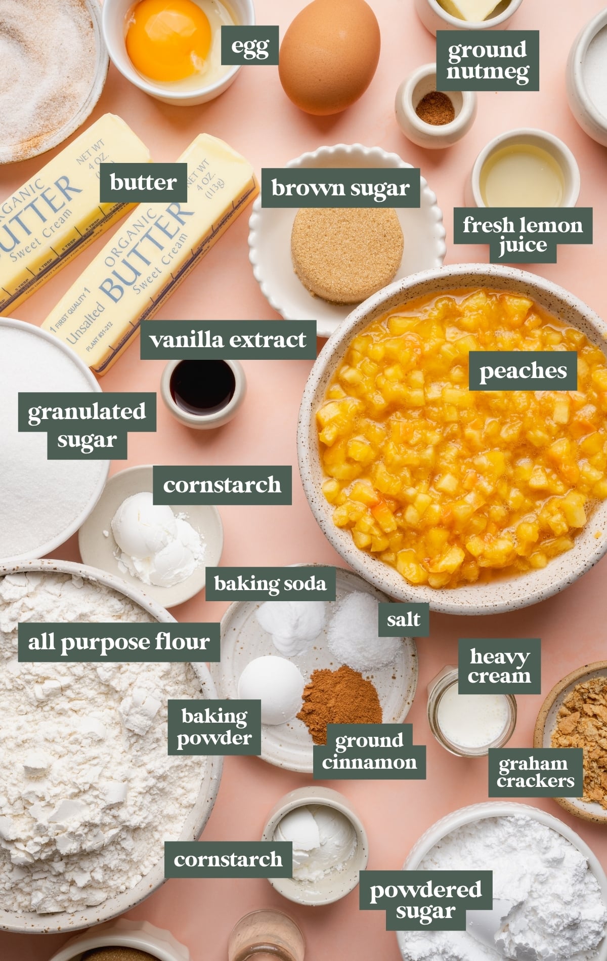 Overhead ingredient collage for peach cobbler cookies with labeled ingredients arranged on a blush pink background. Ingredients include butter, egg, peaches, brown sugar, flour, cinnamon, nutmeg, heavy cream, graham crackers, lemon juice, vanilla extract, cornstarch, baking powder, baking soda, salt, powdered sugar, and granulated sugar.