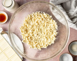 Overhead step-by-step collage showing chopped white chocolate in a glass bowl, hot cream being poured over the chocolate, the mixture resting to melt, stirring until smooth, adding vanilla extract, and stirring again until glossy and combined.