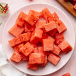 Watermelon cubes placed on a plate with toothpicks in a couple of the pieces.