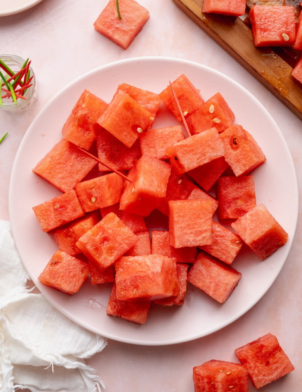 Watermelon cubes placed on a plate with toothpicks in a couple of the pieces.