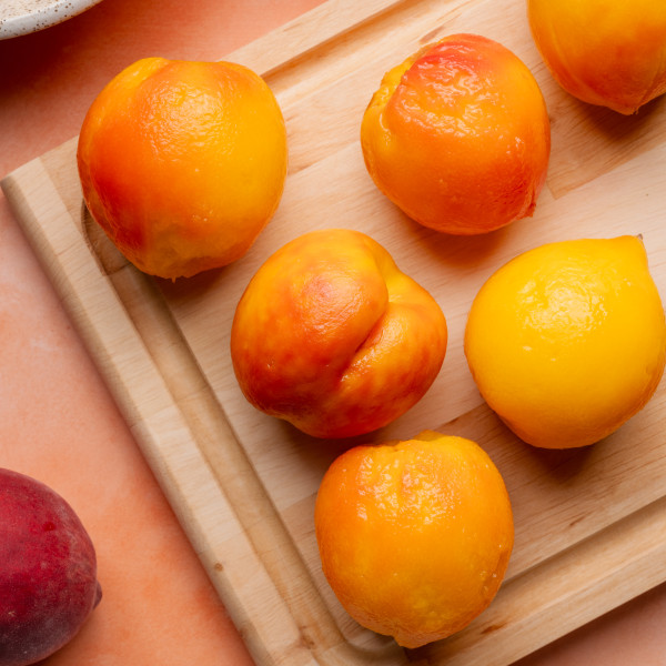 Peeled peaches on cutting board.