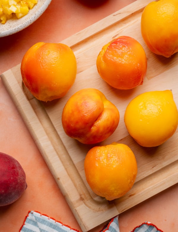 Peeled peaches on cutting board.
