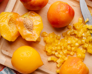 Slicing a peeled peach open and removing the pit before dicing.
