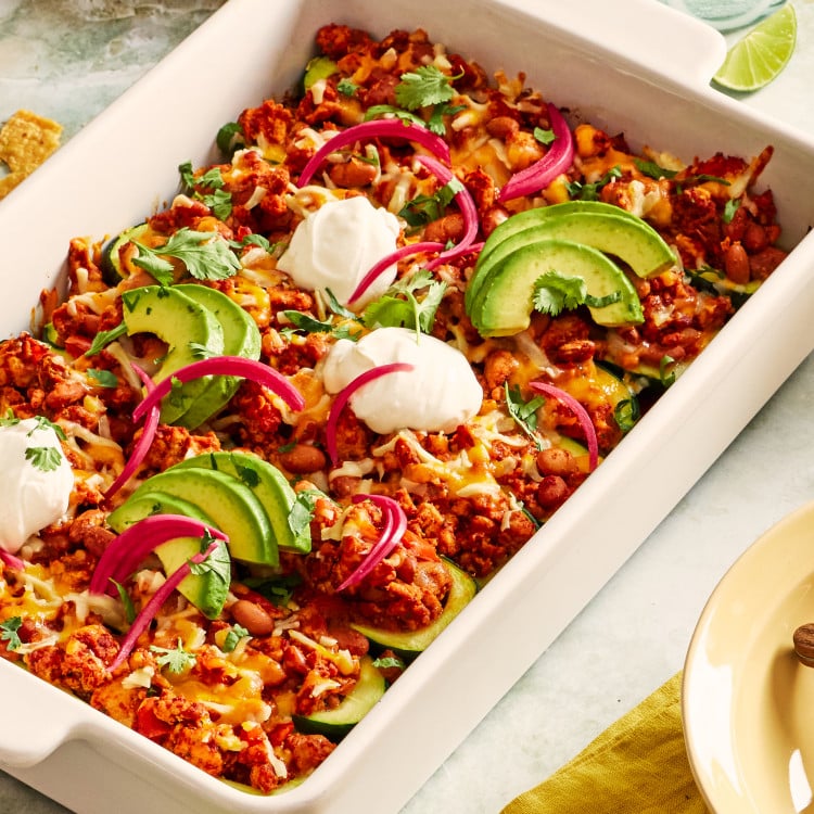 Ground turkey taco zucchini boats topped with sour cream, avocado and pickled red onions.