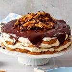 Chocolate chip cookie icebox cake served on cake and topped with extra chocolate chips and cookie pieces.