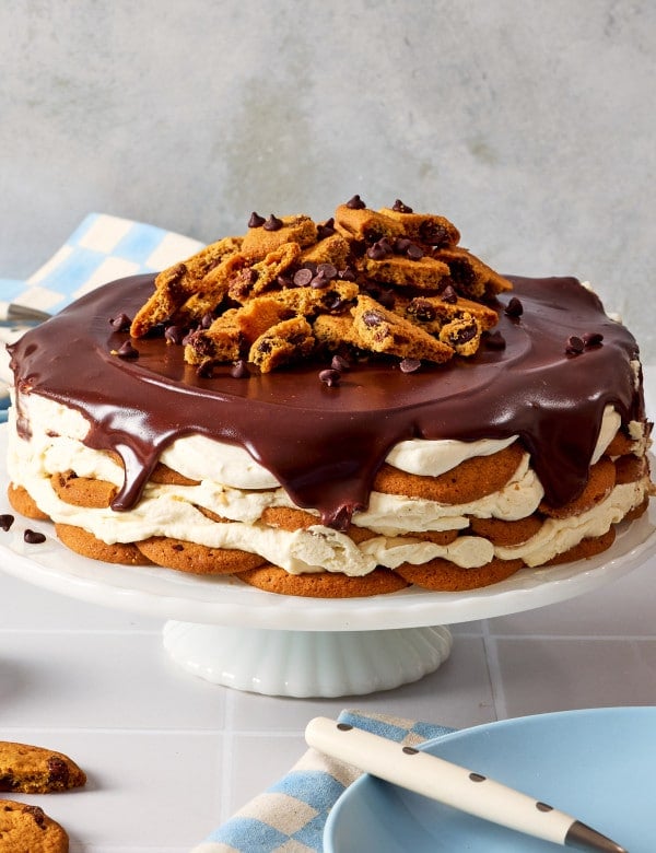 Chocolate chip cookie icebox cake served on cake and topped with extra chocolate chips and cookie pieces.