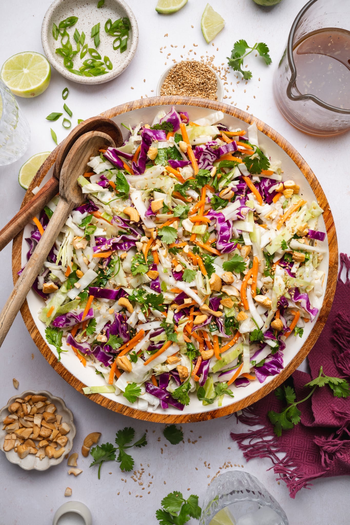 Crunchy asian slaw in a large mixing bowl with two wooden spoons on the side.