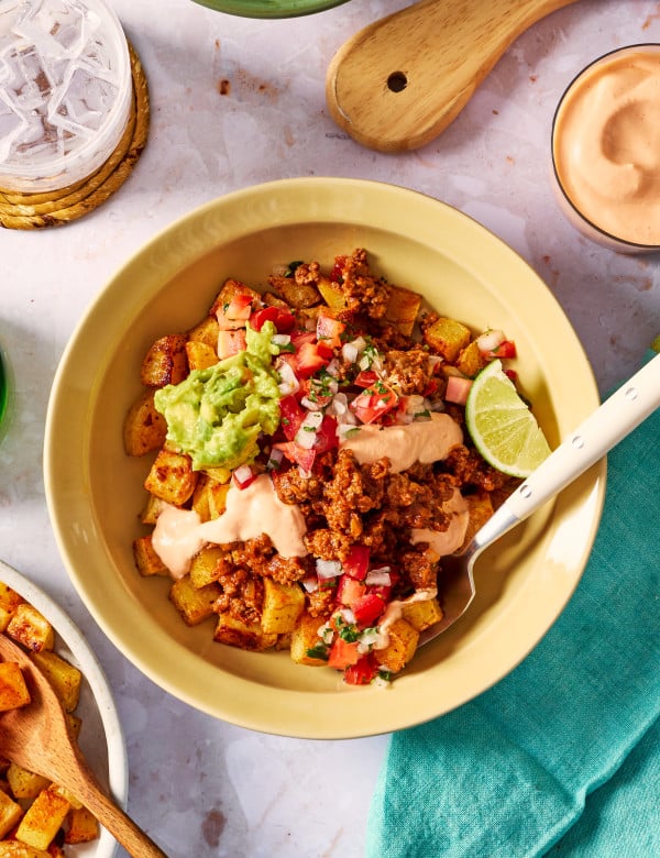 Potato taco bowl with all the toppings and a fork digging into the bowl.