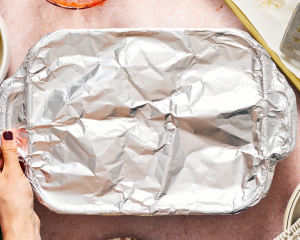 Covering meatball pasta bake with tinfoil before baking.