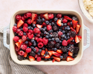 Adding prepped berry filling to prepared baking dish.