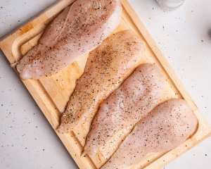 Seasoning sliced and pounded chicken with kosher salt and black pepper before dredging.