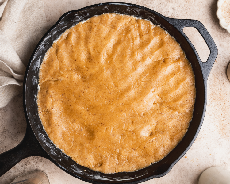 Snickerdoodle cookie dough pressed into cast iron skillet.