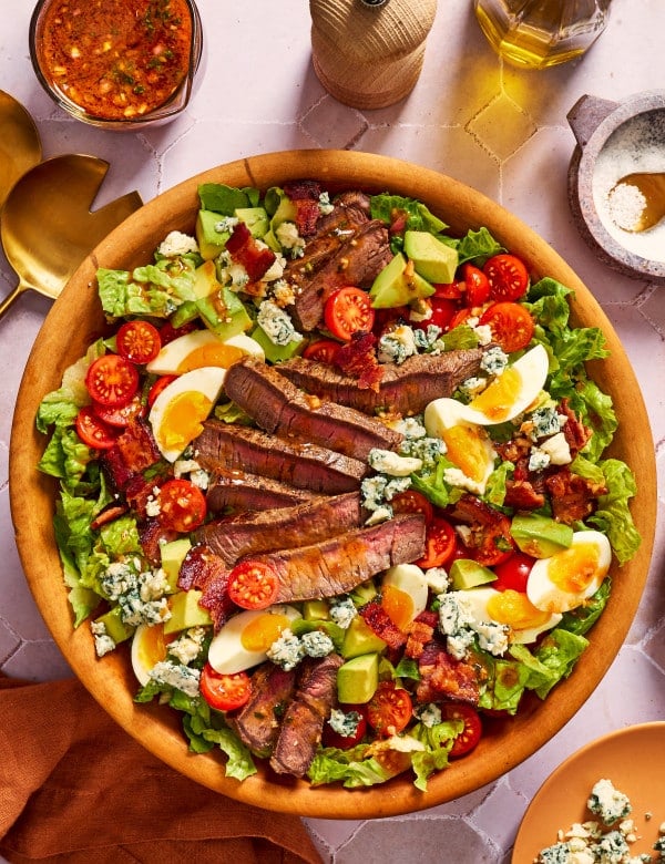 Steak cobb salad with BBQ vinaigrette in wood serving bowl.