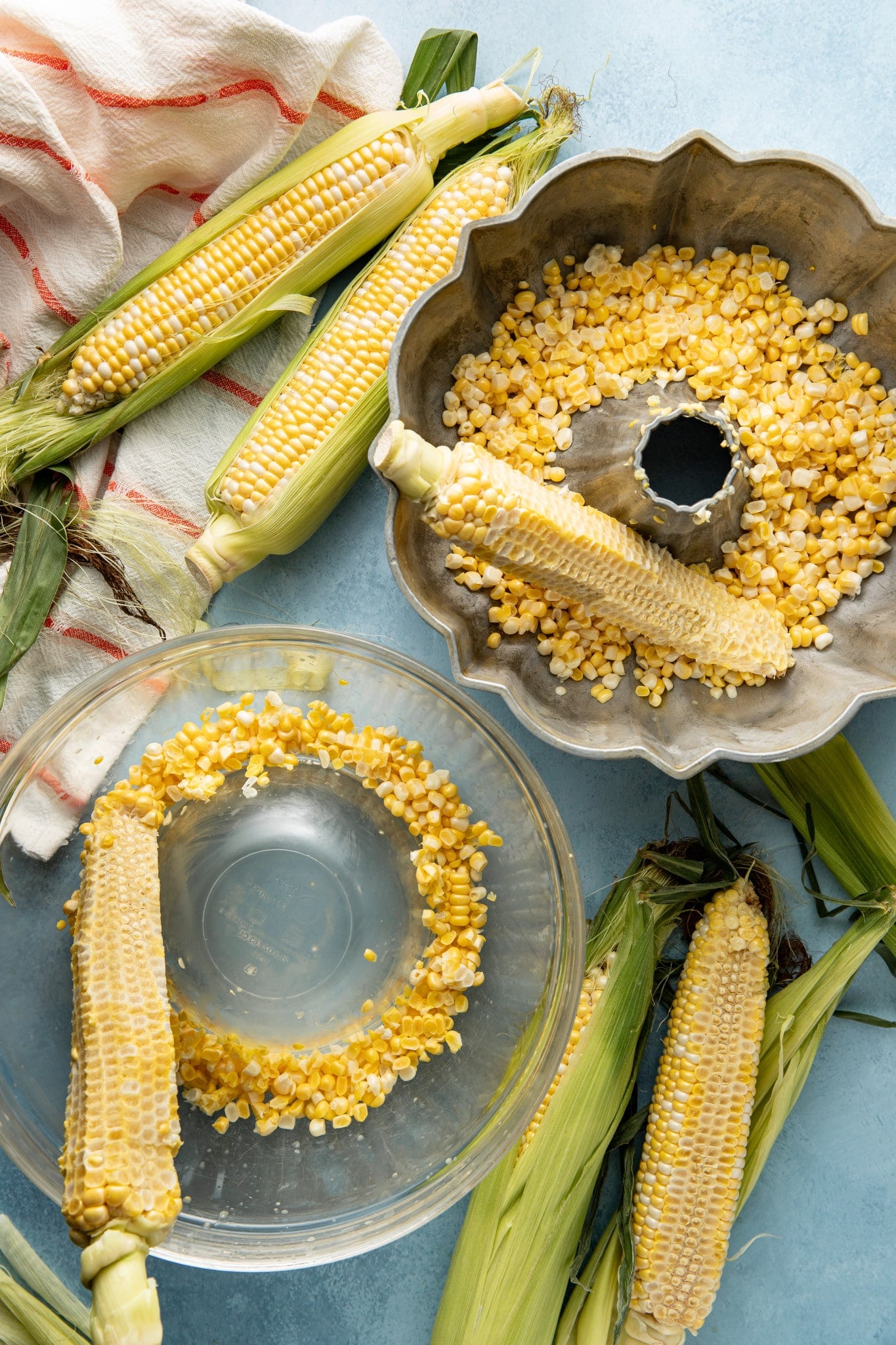One ear of corn cut off the cub using a bundt pan and another ear of corn cut using a small mixing bowl inside a larger mixing bowl.