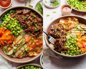 Finished Korean-inspired beef bowls topped with shredded beef, rice, edamame, cucumber salad, carrots, kimchi, sesame seeds, green onions, and sriracha drizzle.