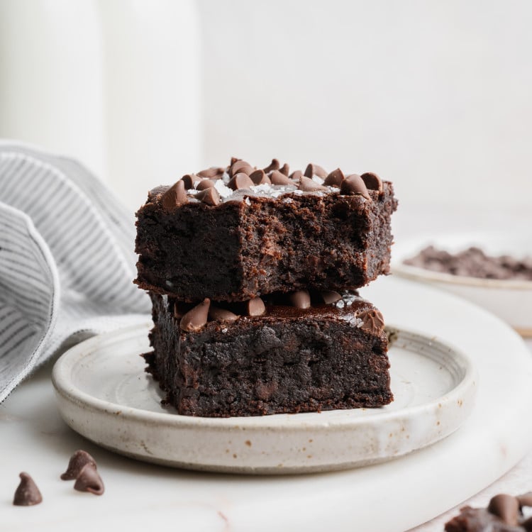 Two black bean brownies stacked on top of each other on a small plate.