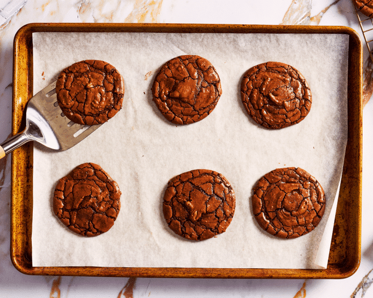 Six cookies baked on baking tray lined with parchment paper.