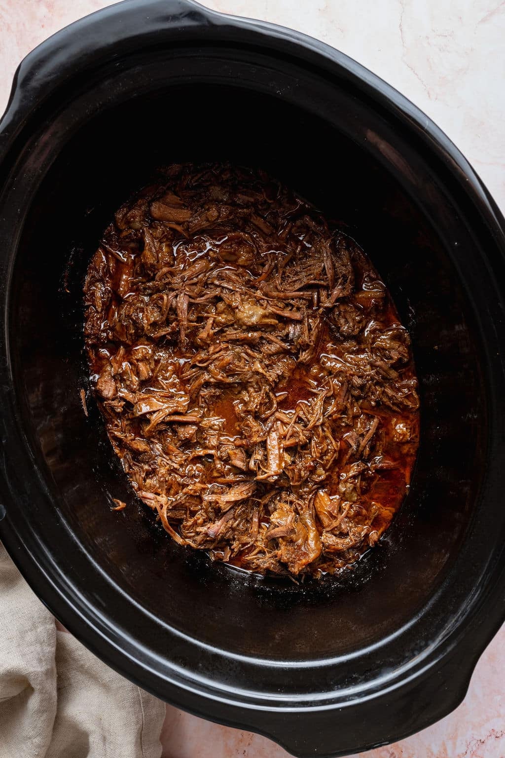 Slow cooker Korean-inspired shredded beef coated in a rich, glossy sauce after cooking, ready to serve or use for beef bowls.