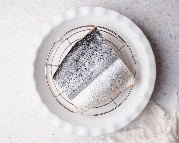 Placing salmon on cooling wrap above plate.