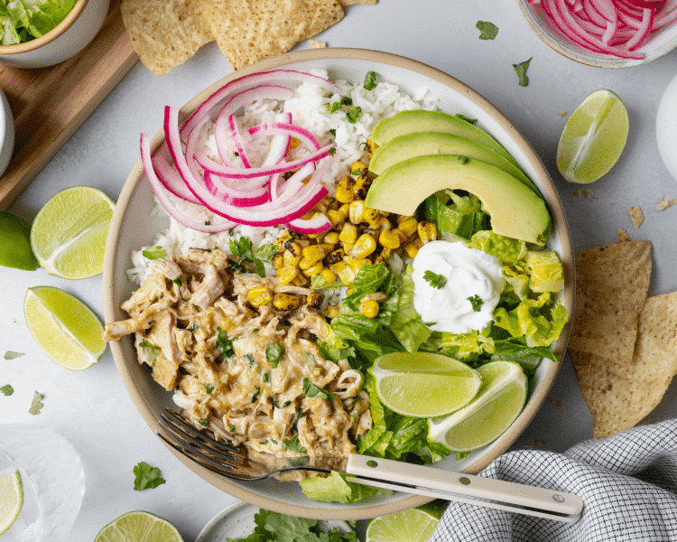 Salsa verde chicken served in bowl with rice and toppings.