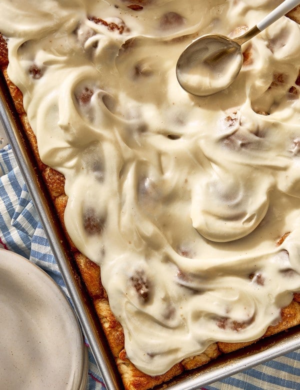 Overhead view of homemade cinnamon roll bites generously covered with smooth cream cheese frosting.