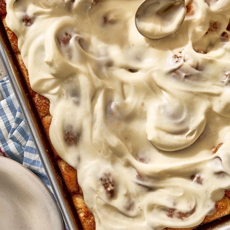 Overhead view of homemade cinnamon roll bites generously covered with smooth cream cheese frosting.