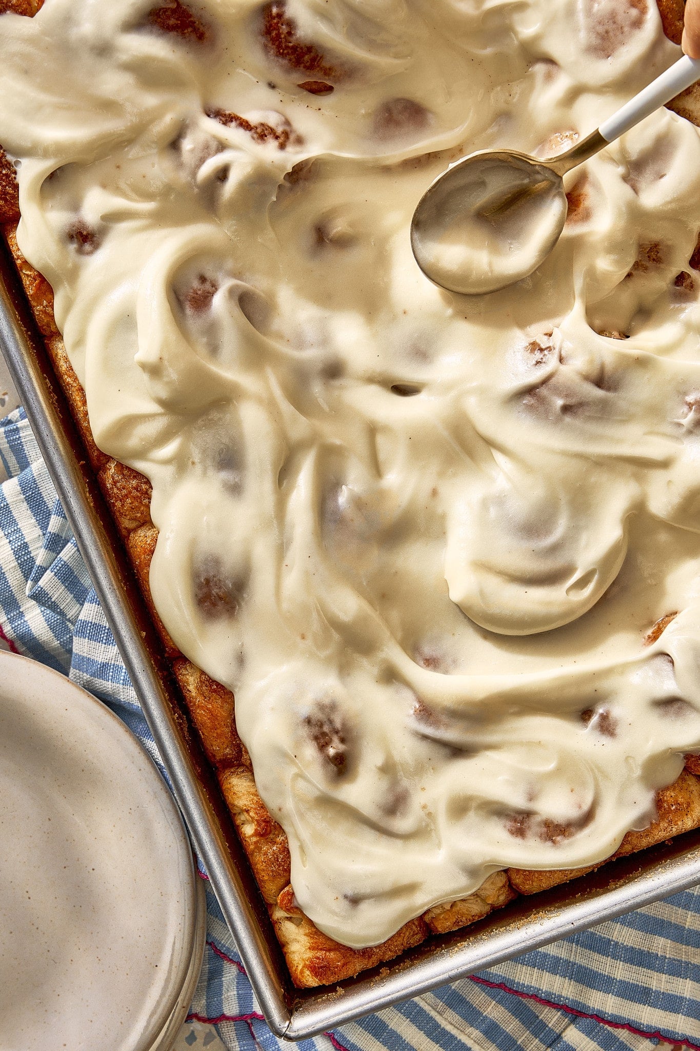 Overhead view of homemade cinnamon roll bites generously covered with smooth cream cheese frosting.