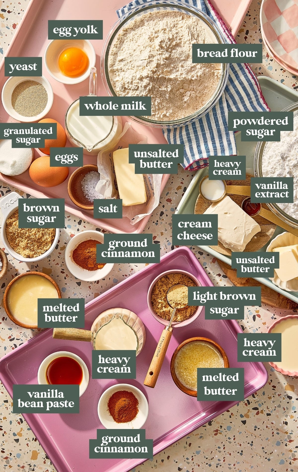 Ingredients for homemade cinnamon roll bites, including bread flour, yeast, milk, eggs, butter, brown sugar, cinnamon, heavy cream, cream cheese, powdered sugar, and vanilla.