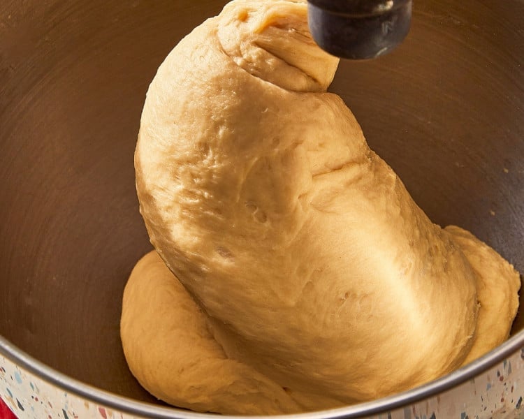 Soft, smooth cinnamon roll dough kneading with a dough hook in the bowl of a stand mixer.
