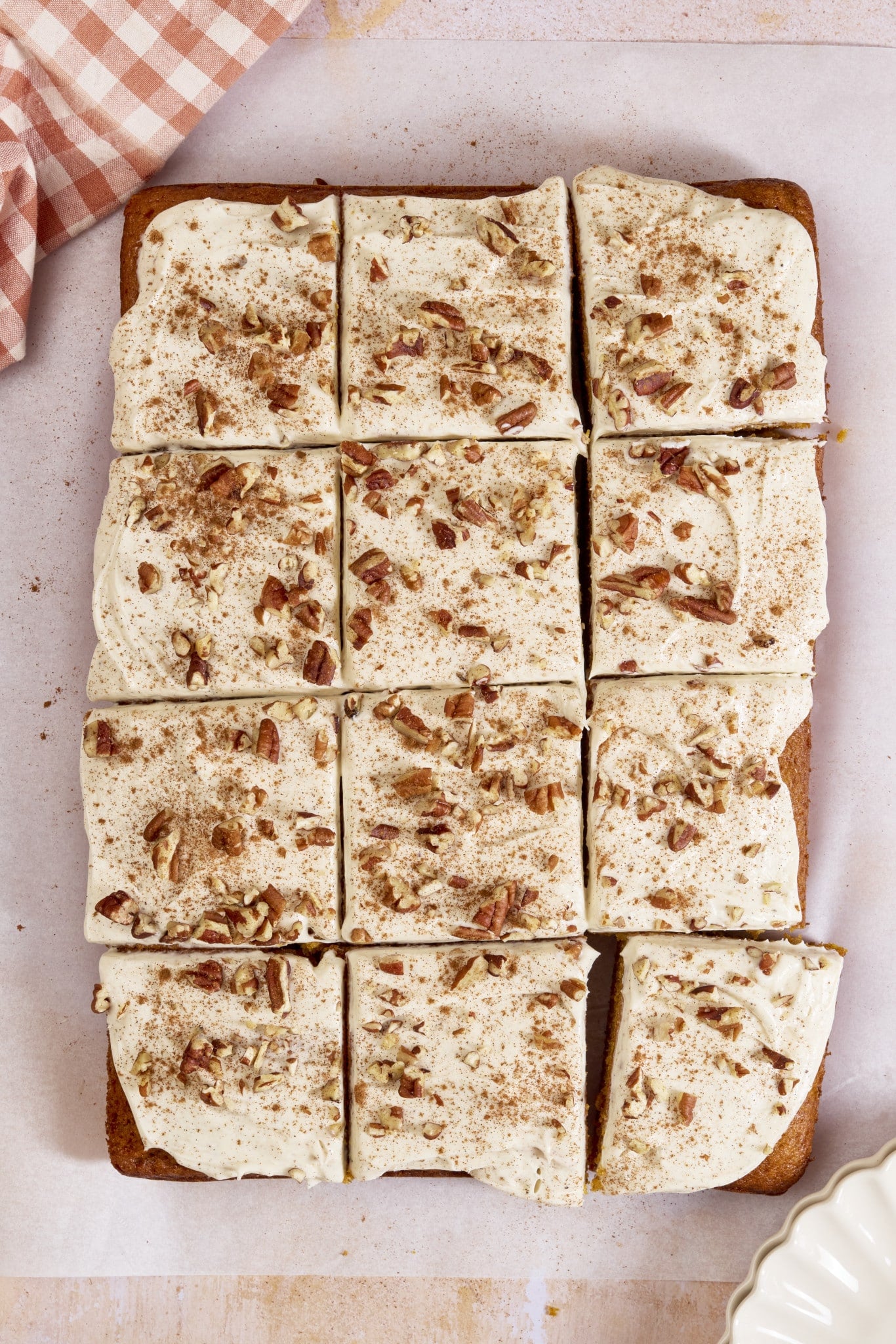 Pumpkin sheet cake cut into twelve slices.