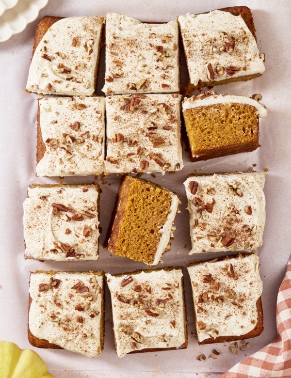 Pumpkins spice sheet cake cut into pieces with two pieces turned on their sides to see inside of cake crumb.
