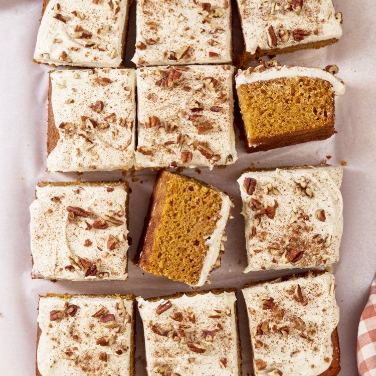 Pumpkins spice sheet cake cut into pieces with two pieces turned on their sides to see inside of cake crumb.