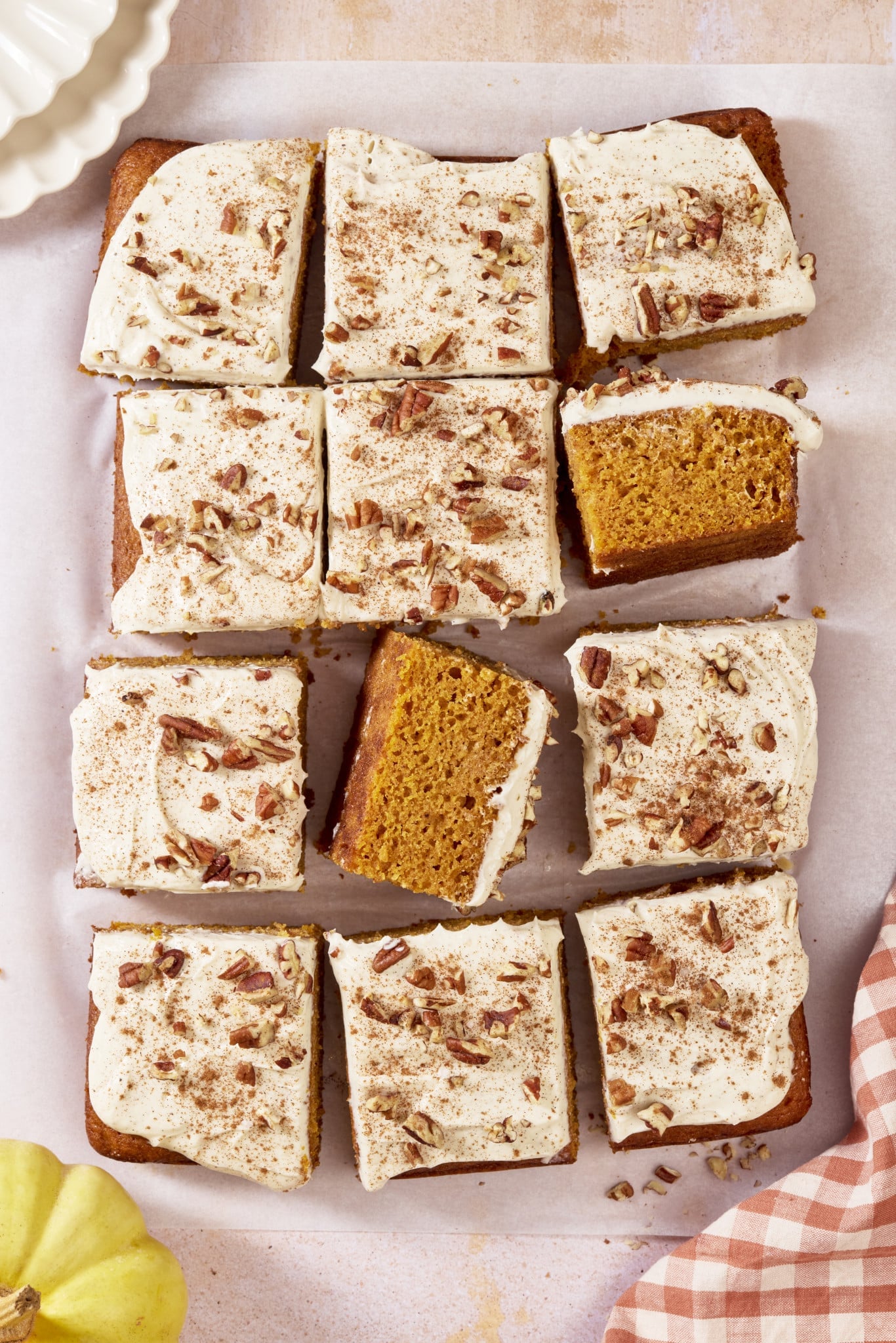 Pumpkins spice sheet cake cut into pieces with two pieces turned on their sides to see inside of cake crumb.