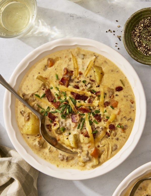 Cheeseburger soup in a bowl with a spoon digging in.